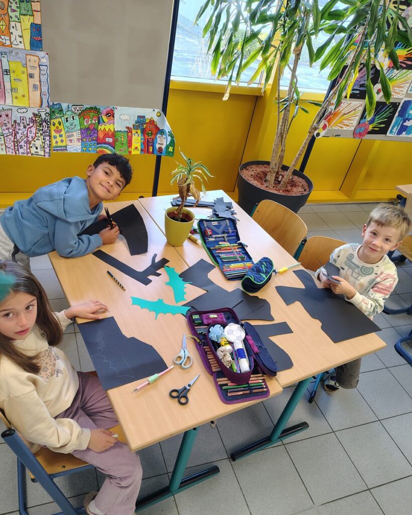Kinder schneiden Halloween-Bilder aus schwarzem Papier aus